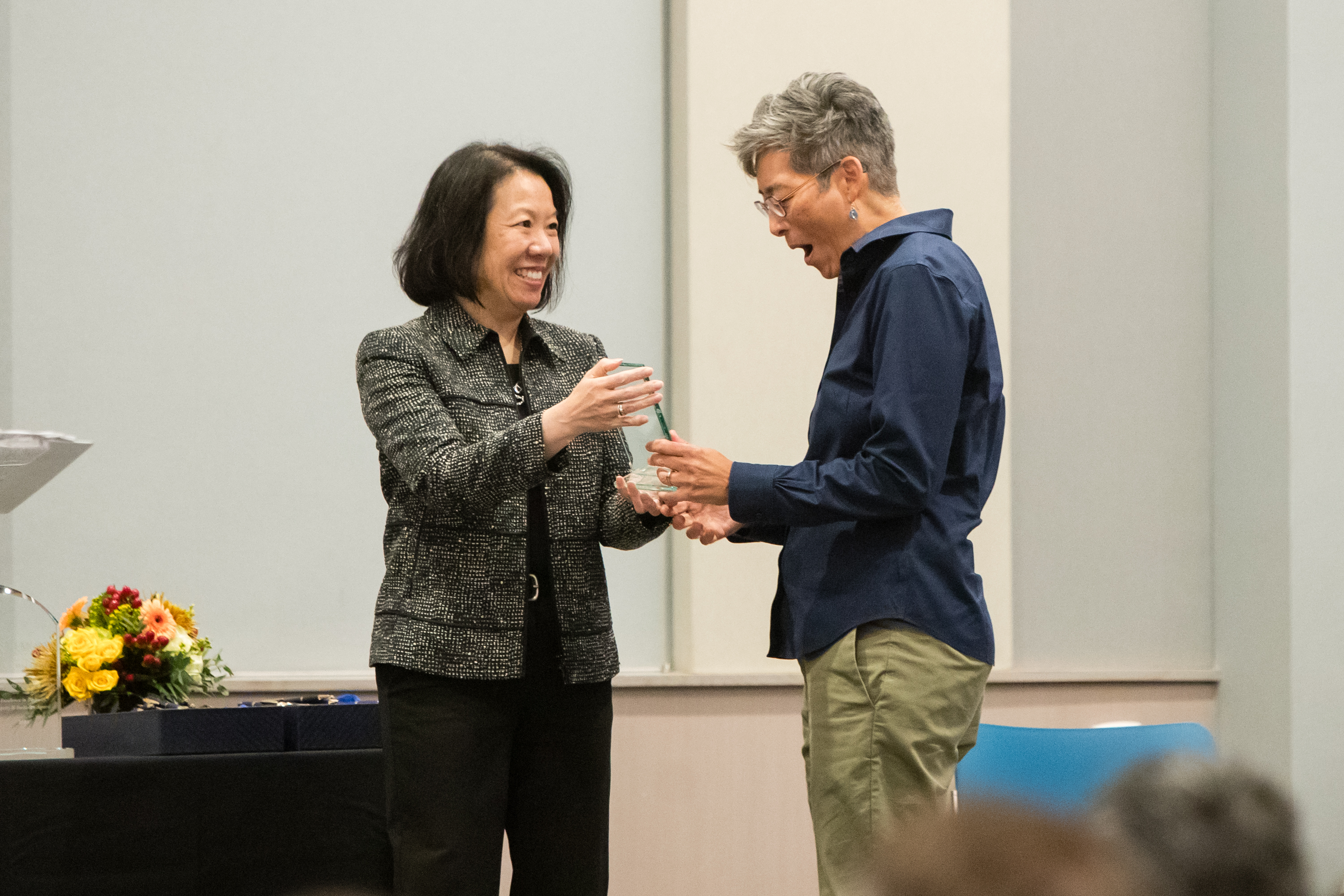 Faculty member accepts glass award on stage from dean