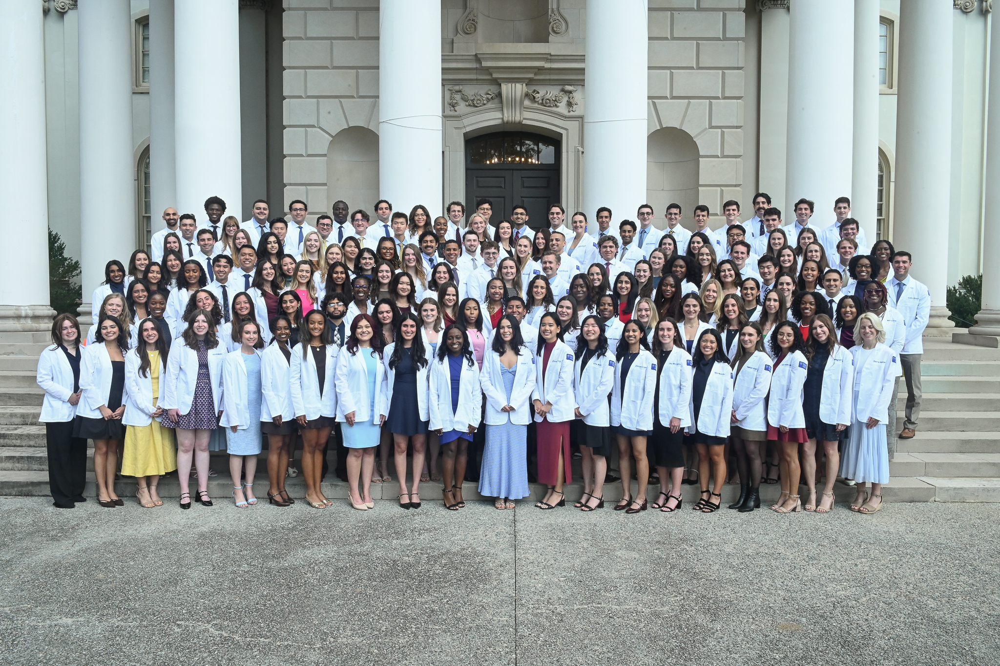 large group of MD students wearing white coats on a large outdoor staircase