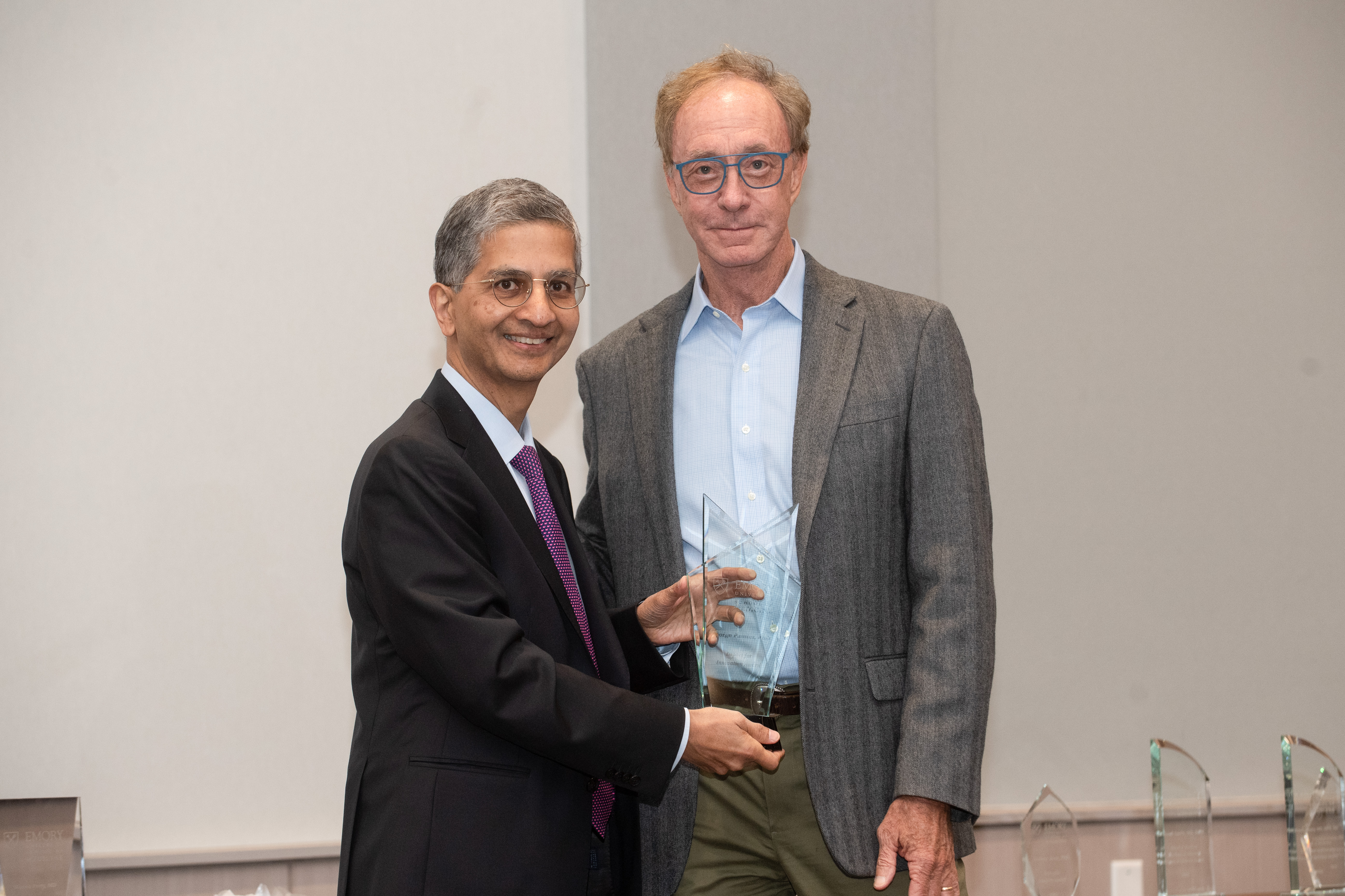 Two men standing holding a glass award