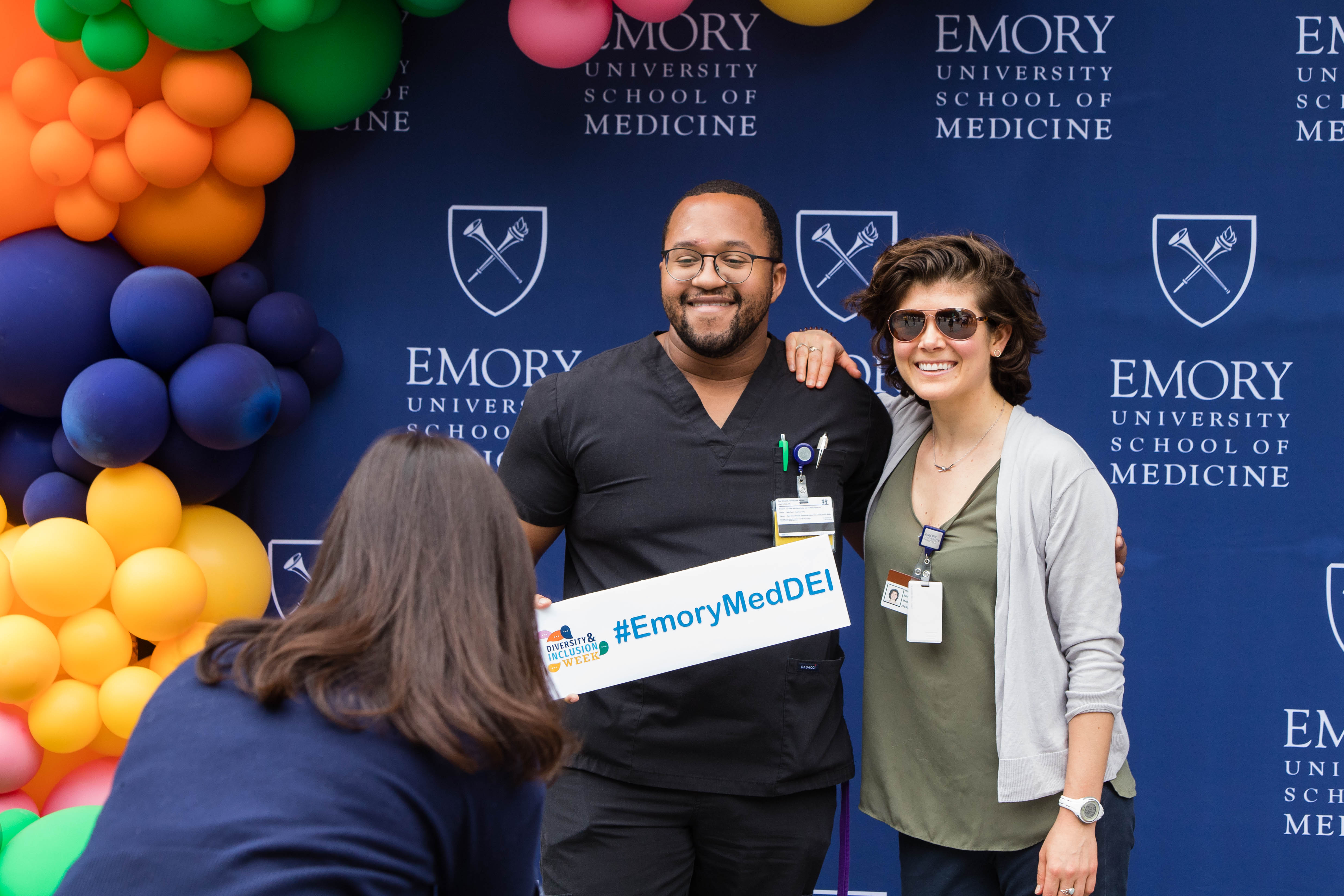 Two people pose for a photo in front of a backdrop