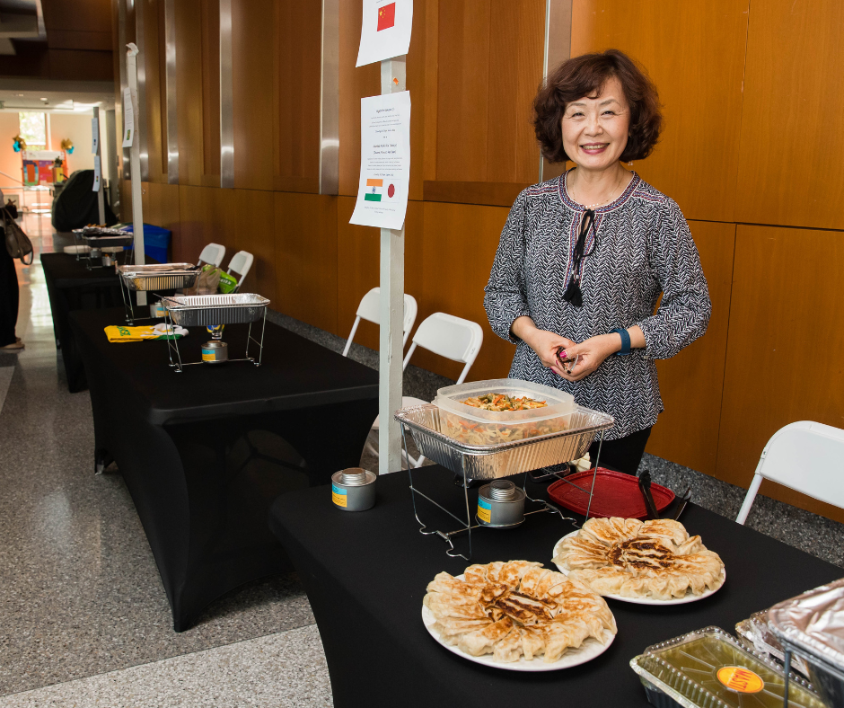 Woman stands in front of a table of food smiling.