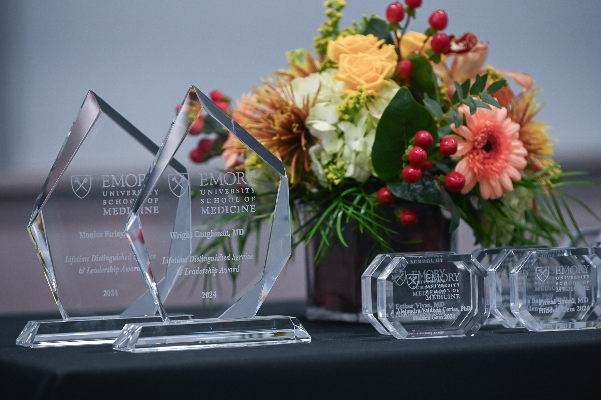 Glass awards and flowers sit on table.