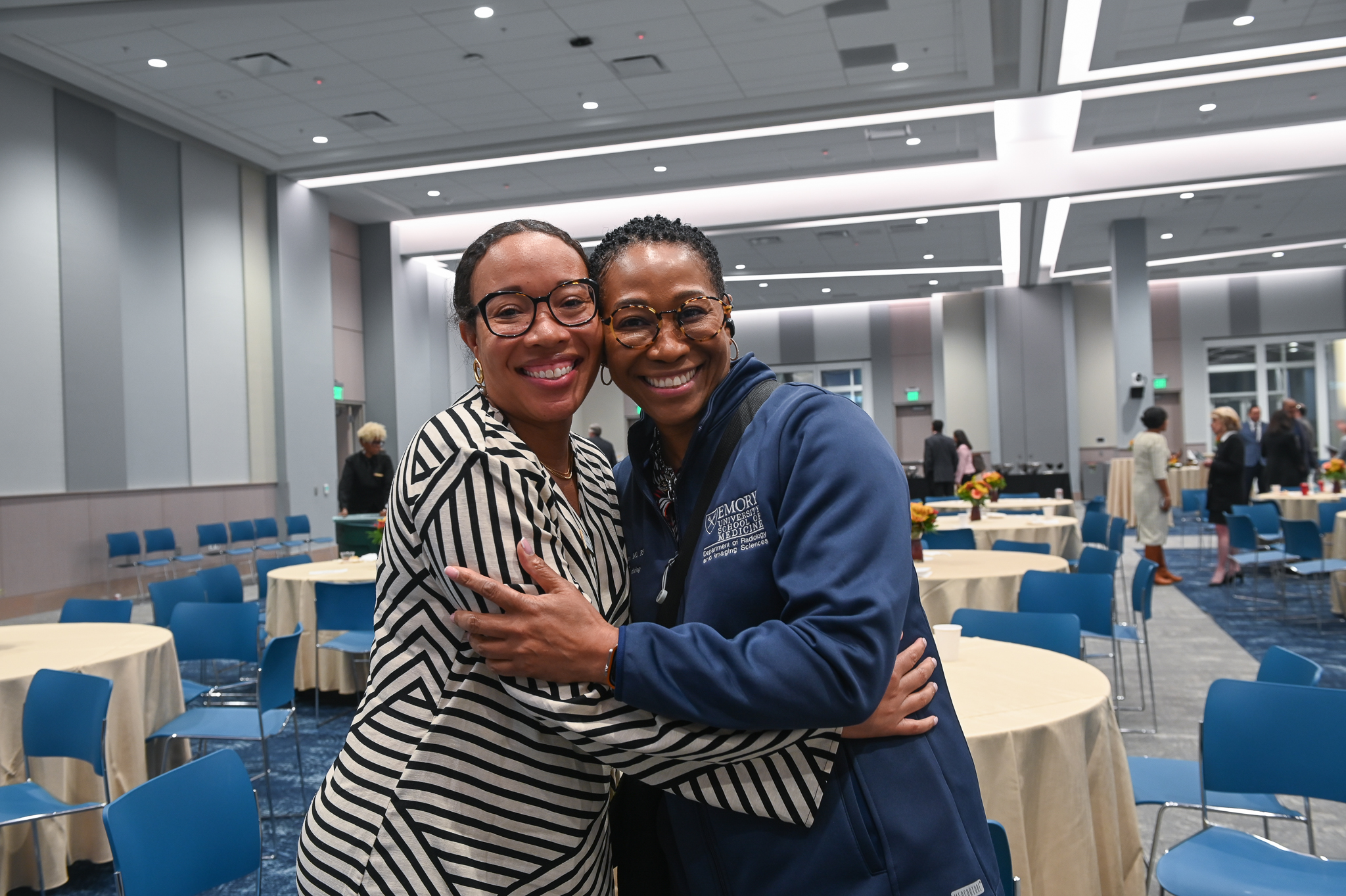 Two women smile and hug for a photo.