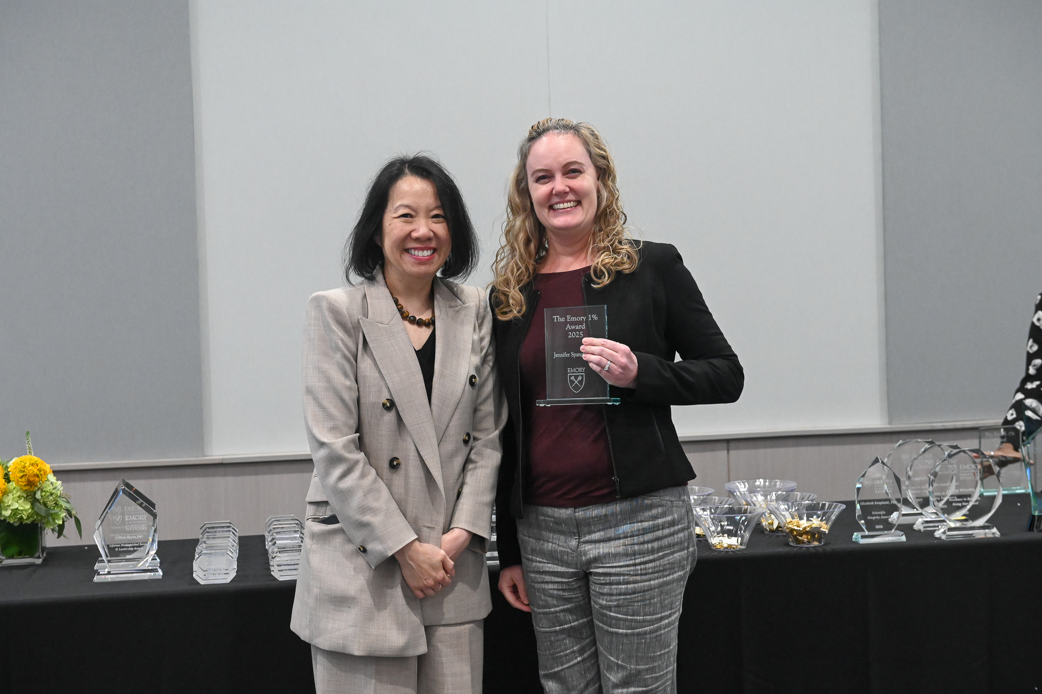 Faculty member accepts glass award on stage with dean.