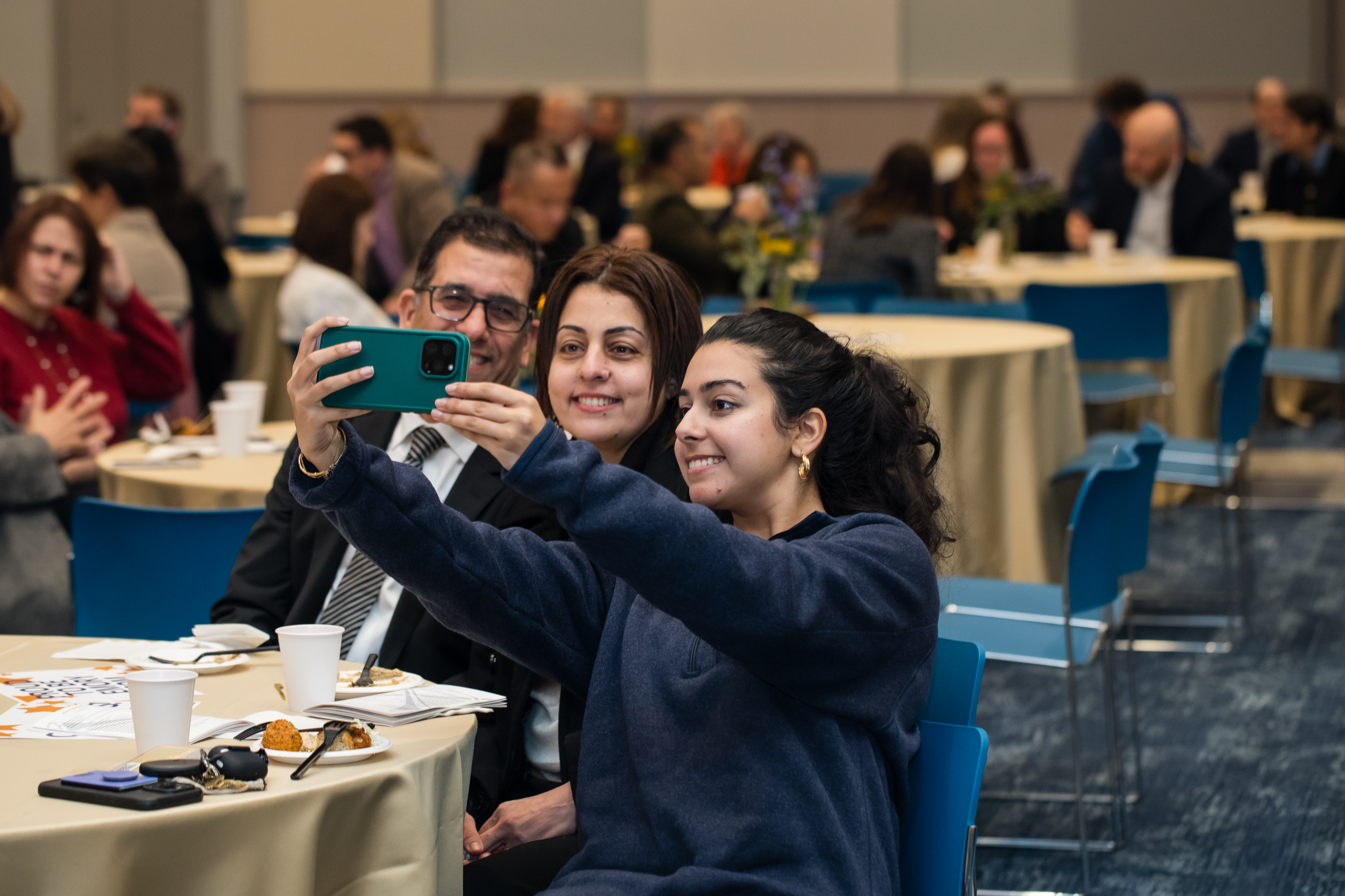 Three people take a selfie sitting at a table.