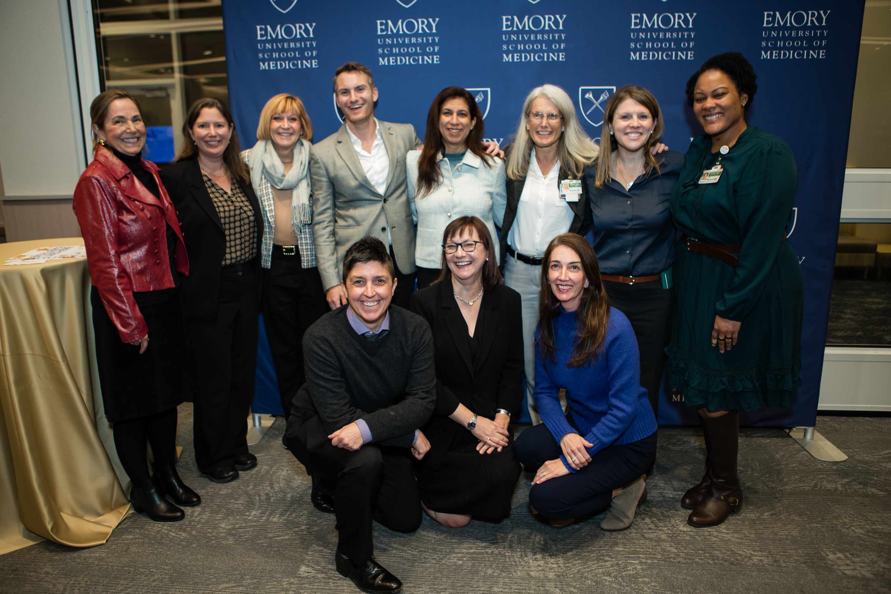 Large group of people smiling for a photo in front of a step and repeat.