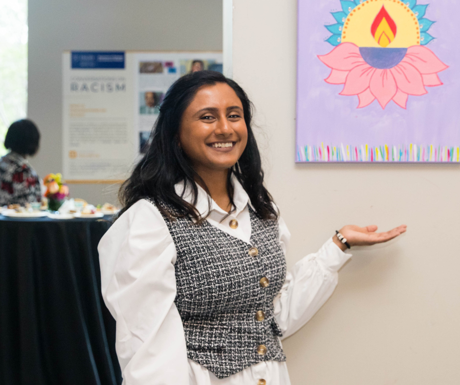 Student stands in front of her art work painted on canvas