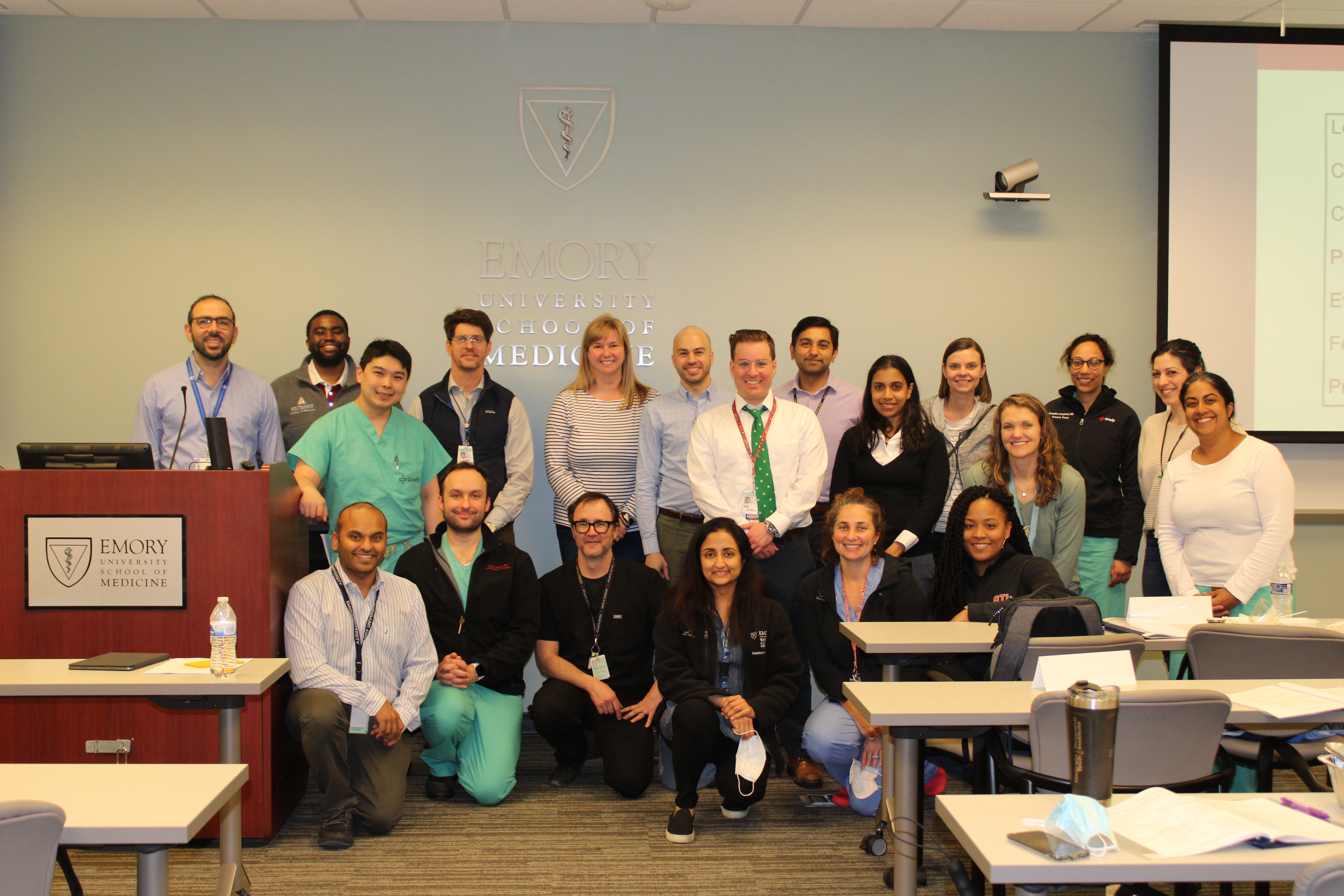 Group of faculty pose for a group photo with University School of Medicine logo behind them