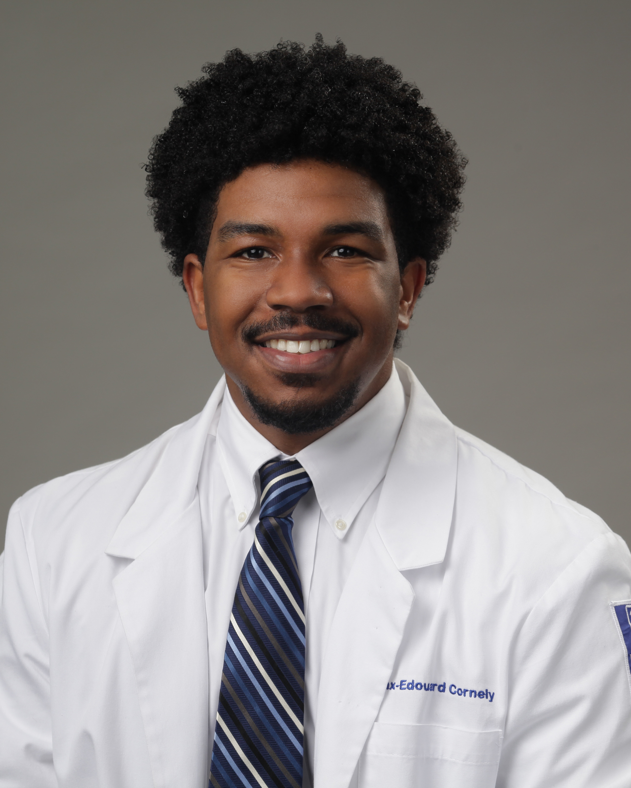 headshot man in white coat wearing a tie