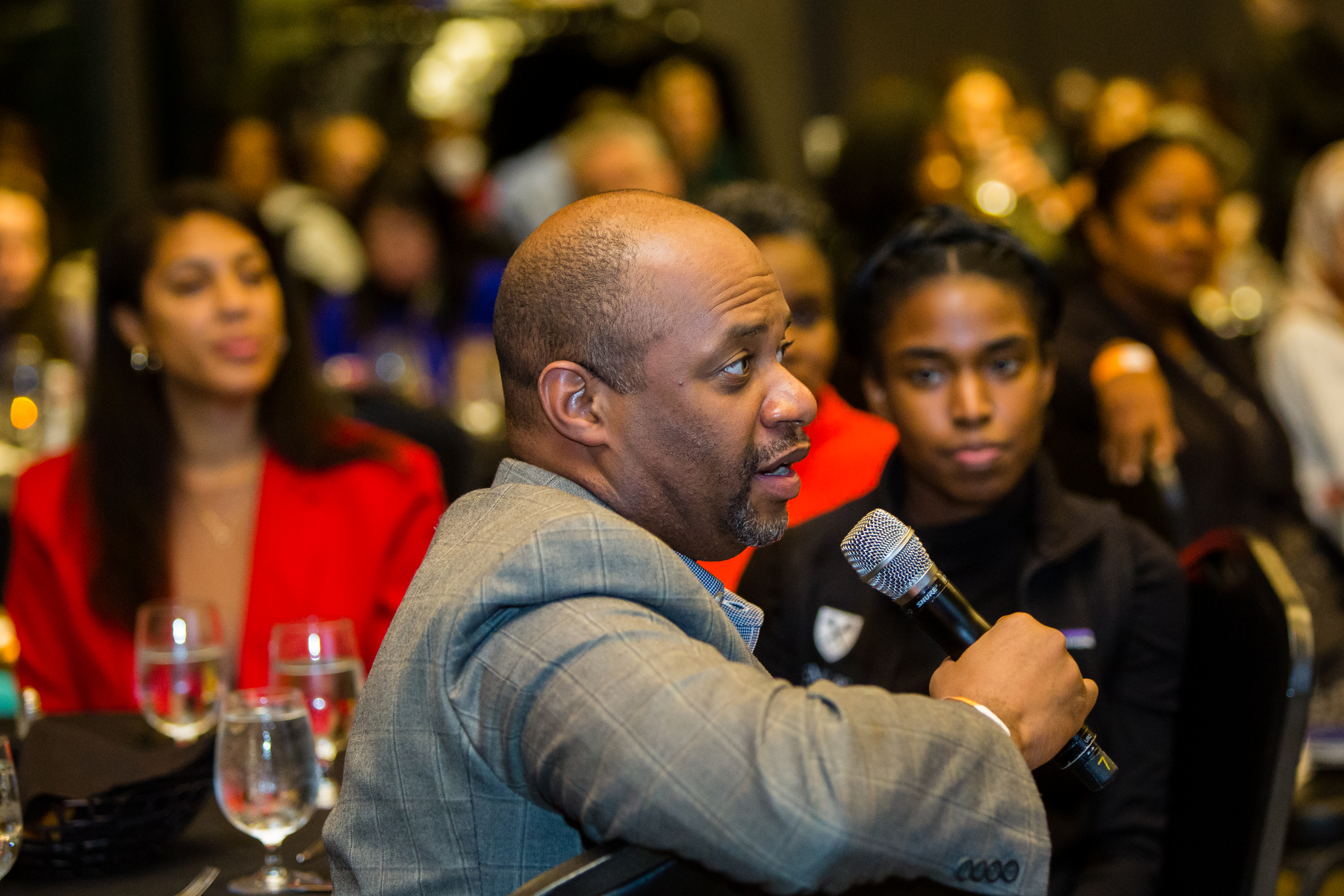 One man speaks into microphone with others looking on