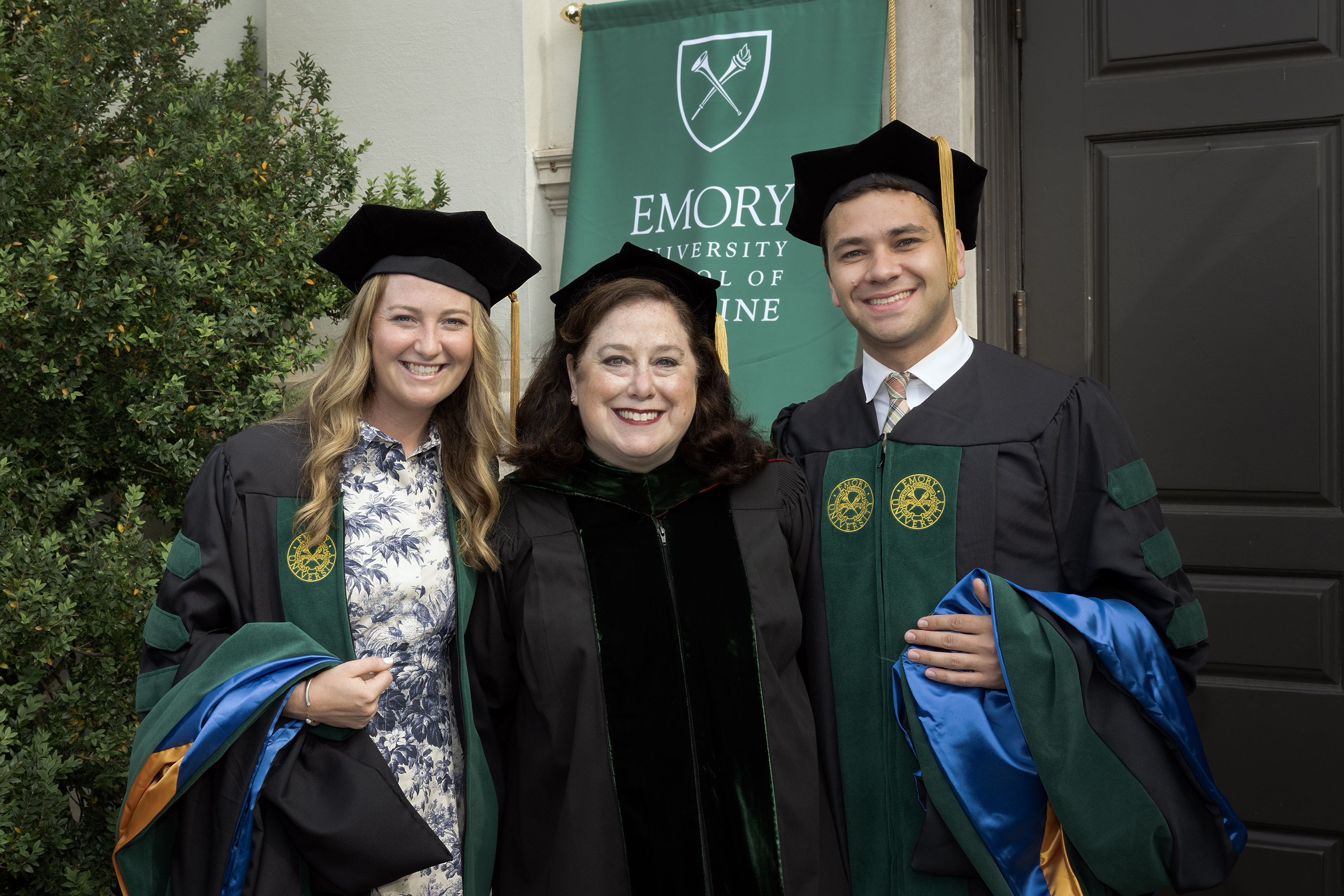 graduates standing in front of a banner with a teacher
