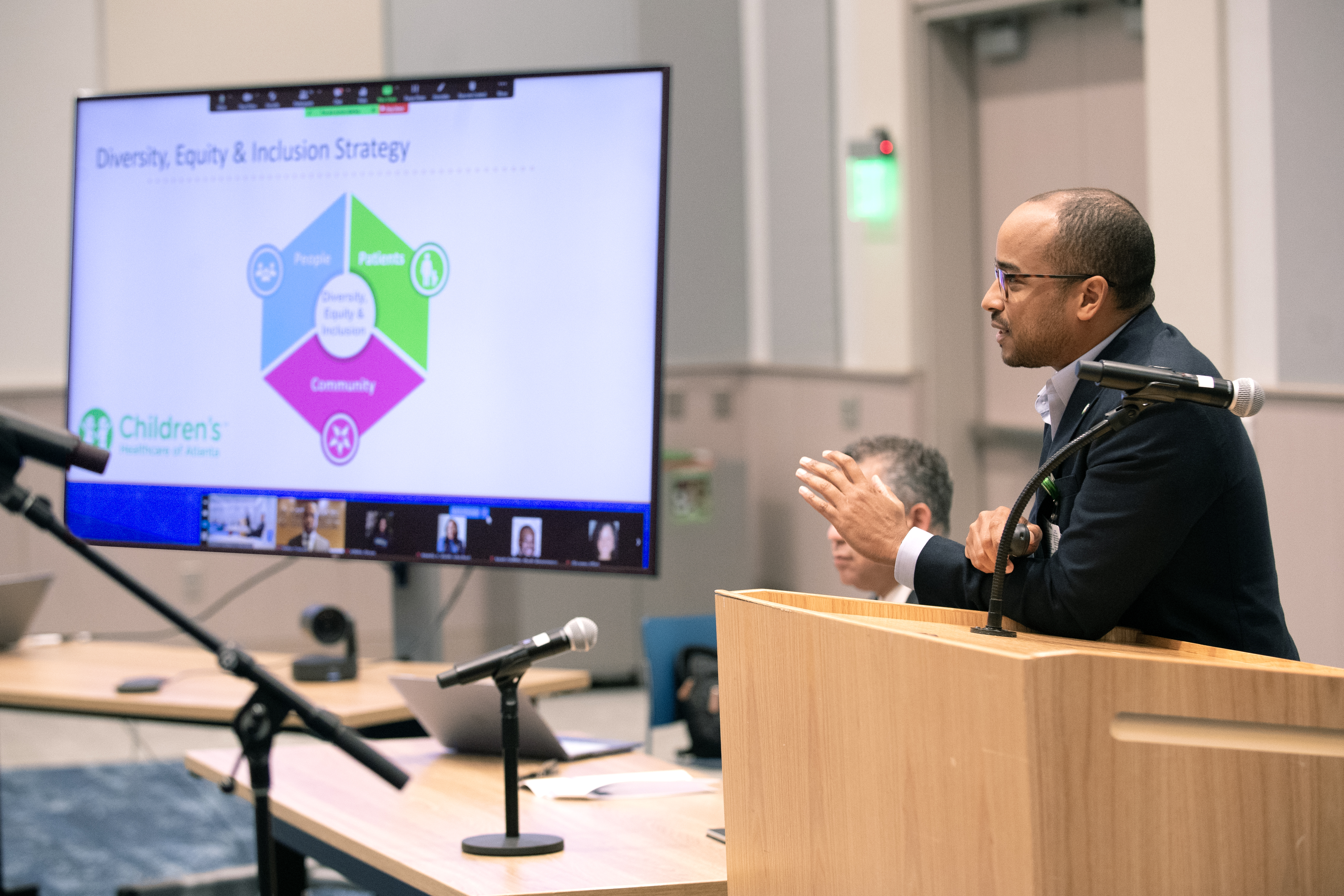 Man stands at a podium presenting and looking at a presentation