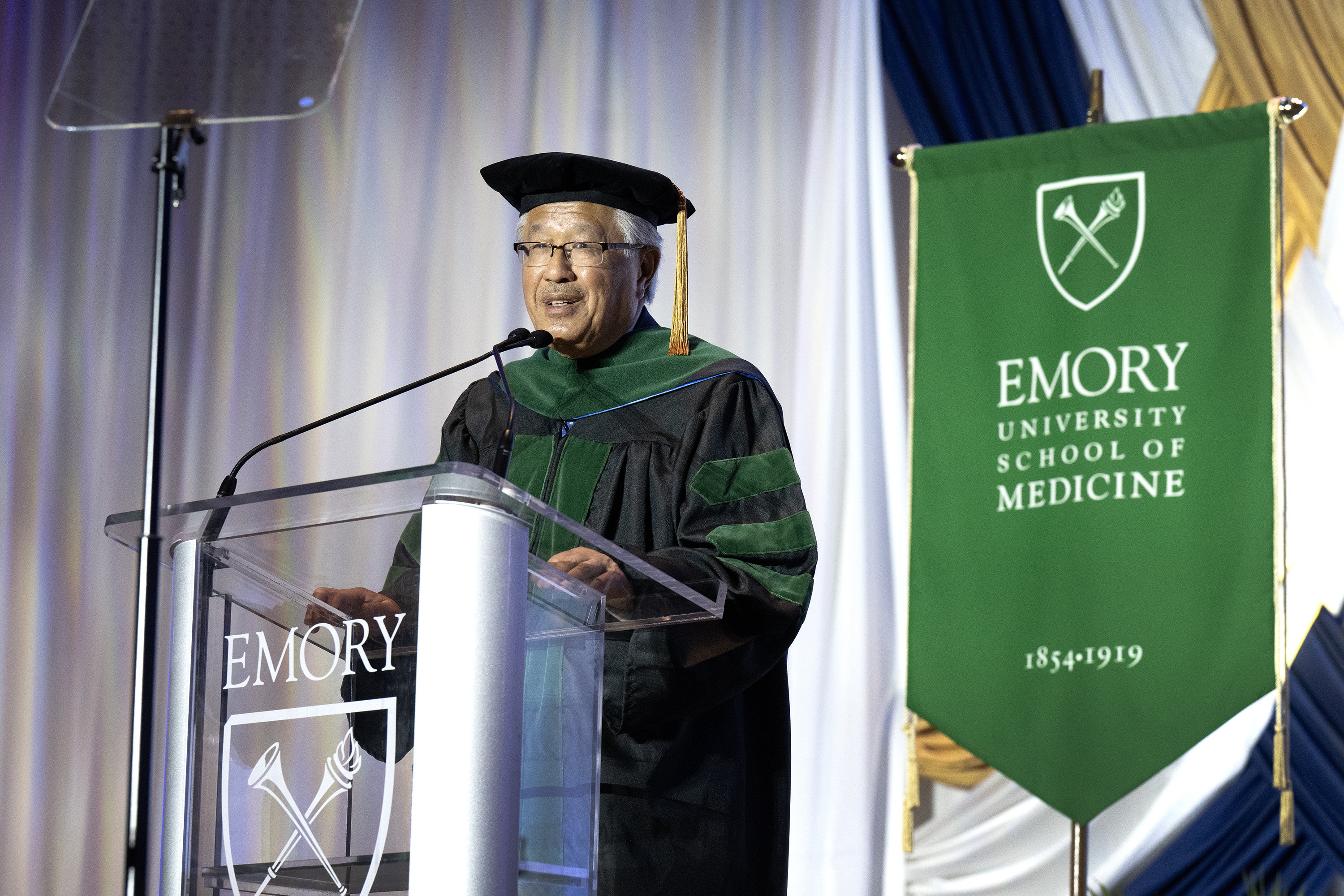 Man in cap and gown in front of glass podium