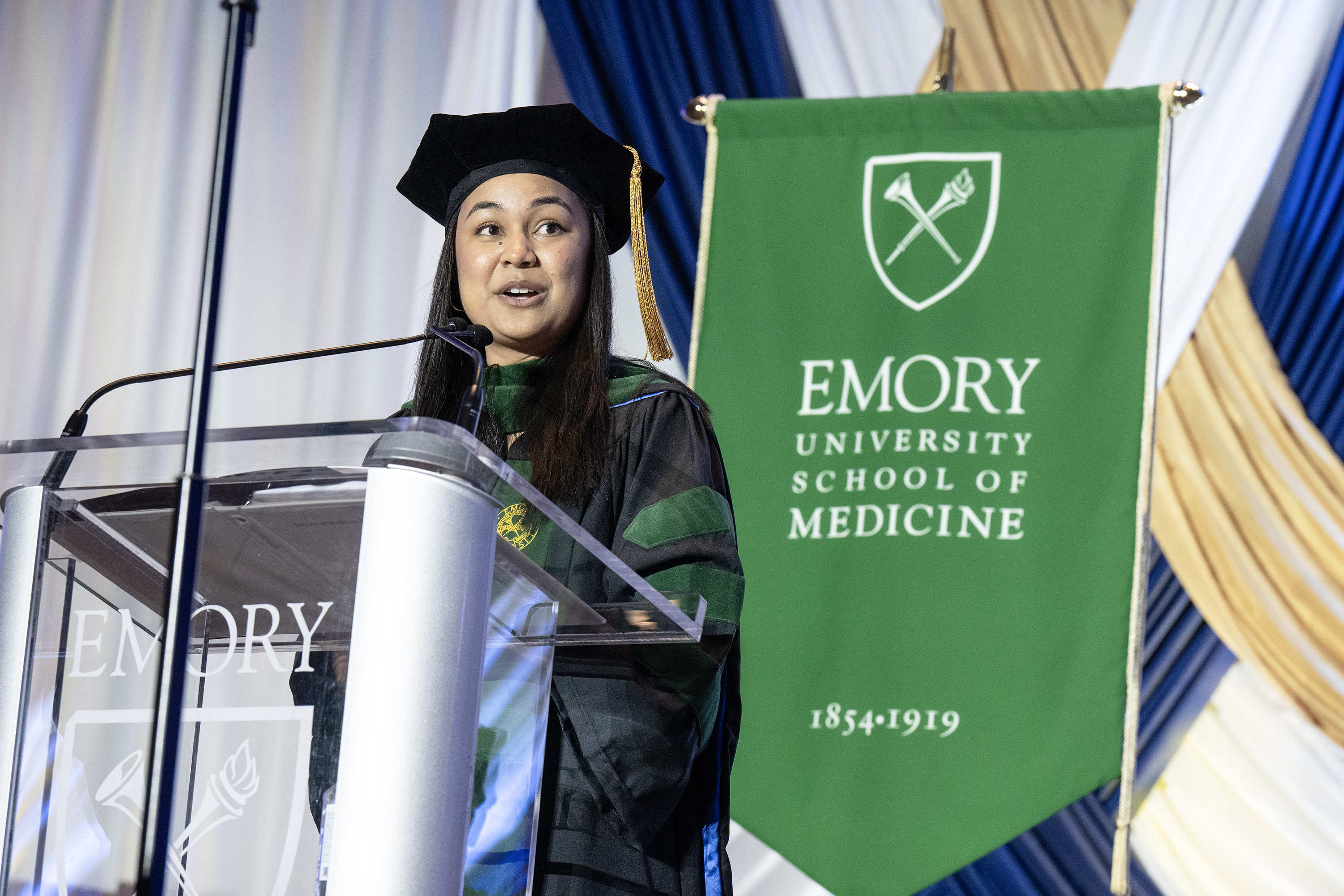 woman in cap and gown in front of glass podium