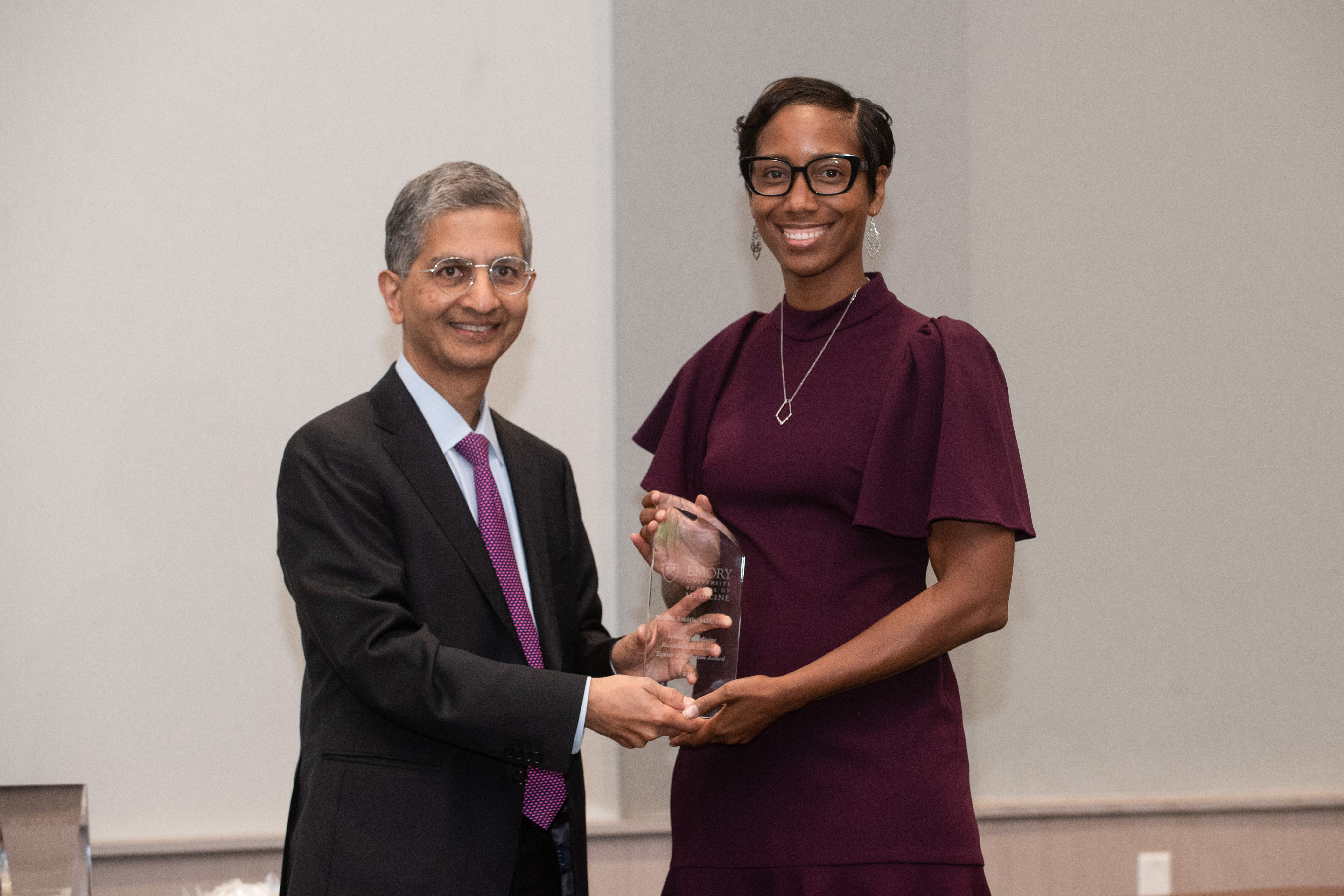 Two people standing one holding a glass award