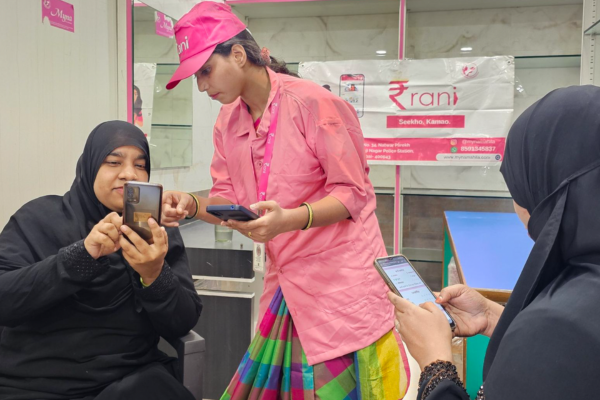 Azra Ismail helps two women using cell phones.