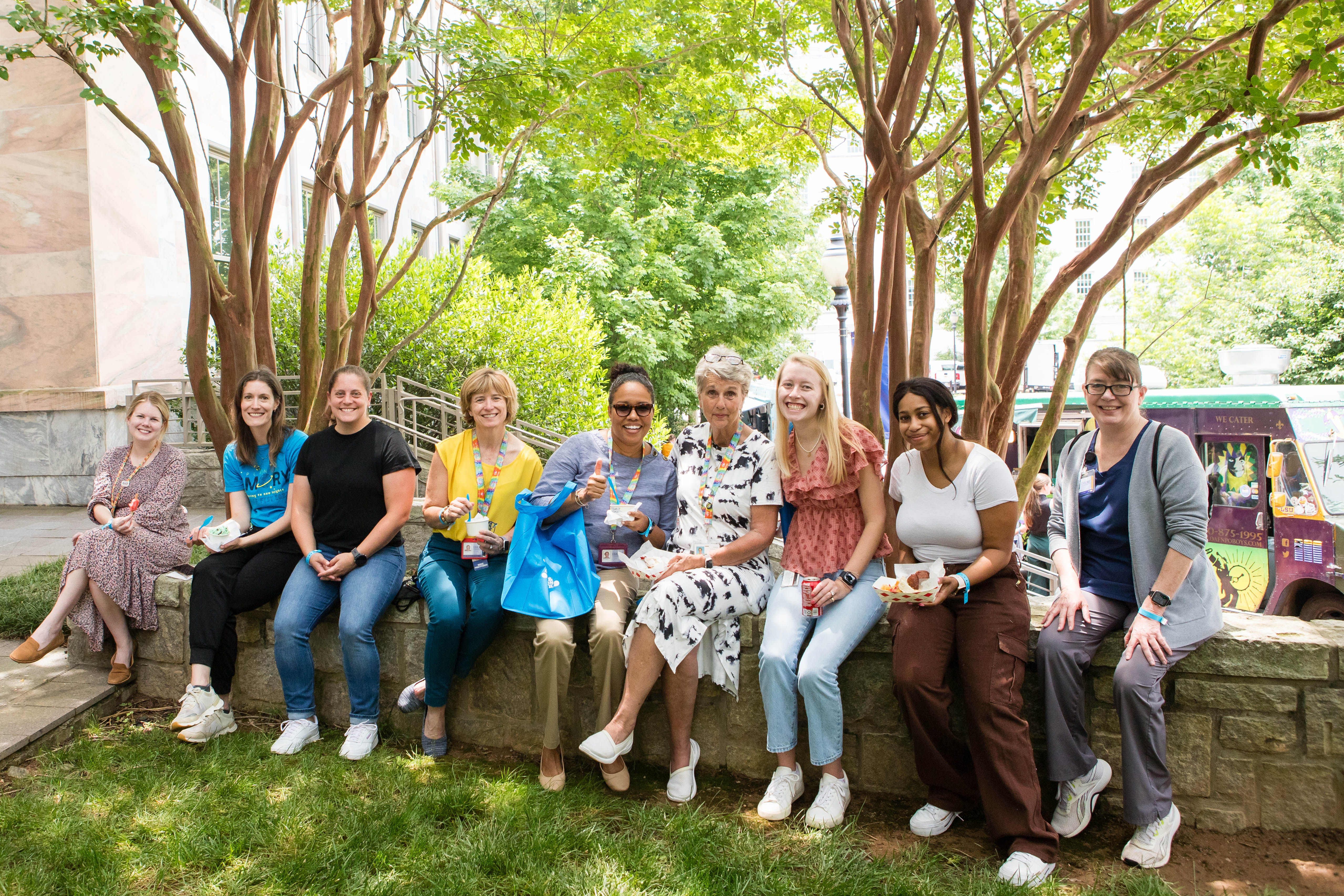 Group photo of people sitting under trees outside at an event. 