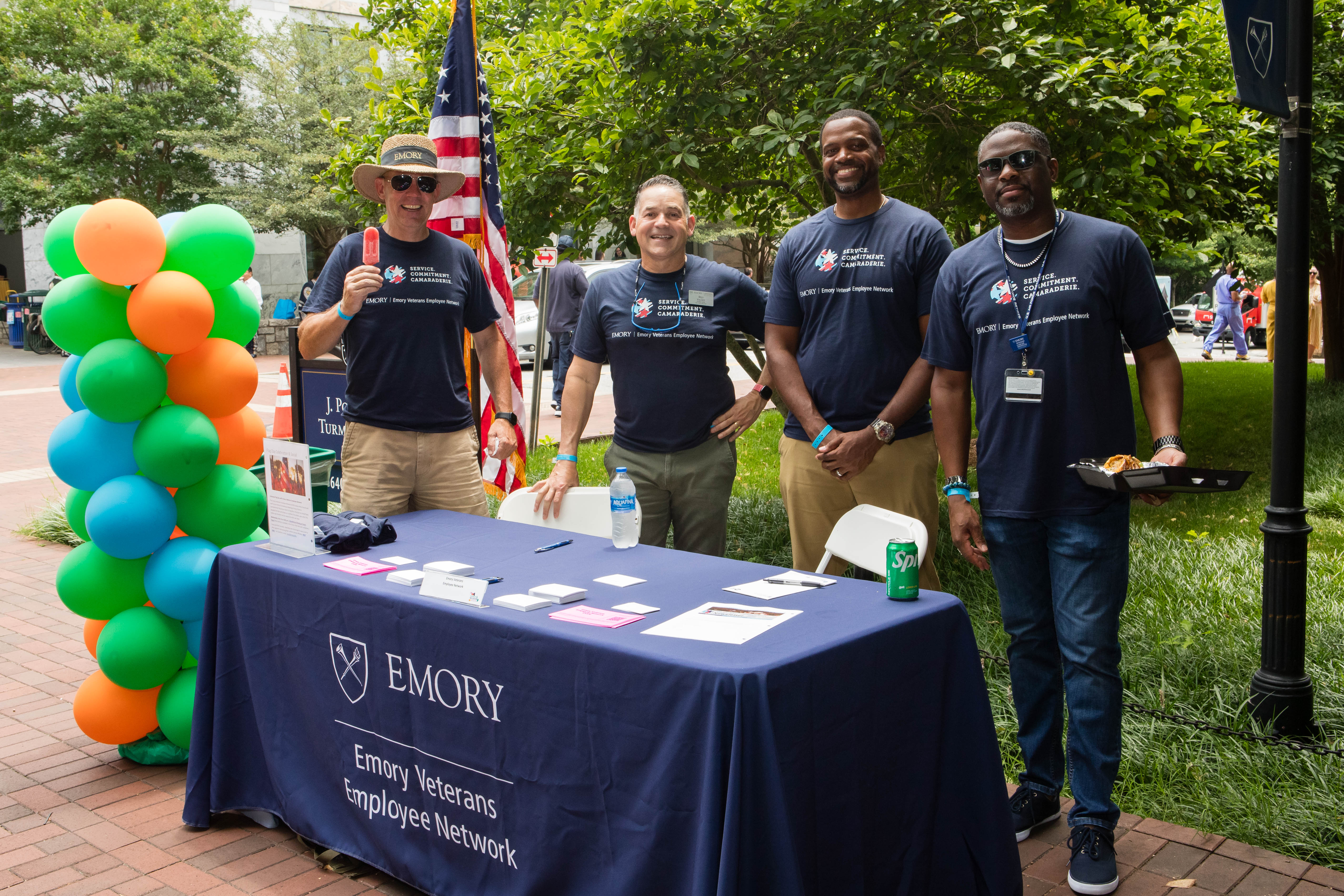 Veterans affinity group stand at table and smile.
