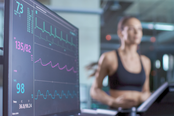 Stock image of woman running on treadmill with monitor in front of her.