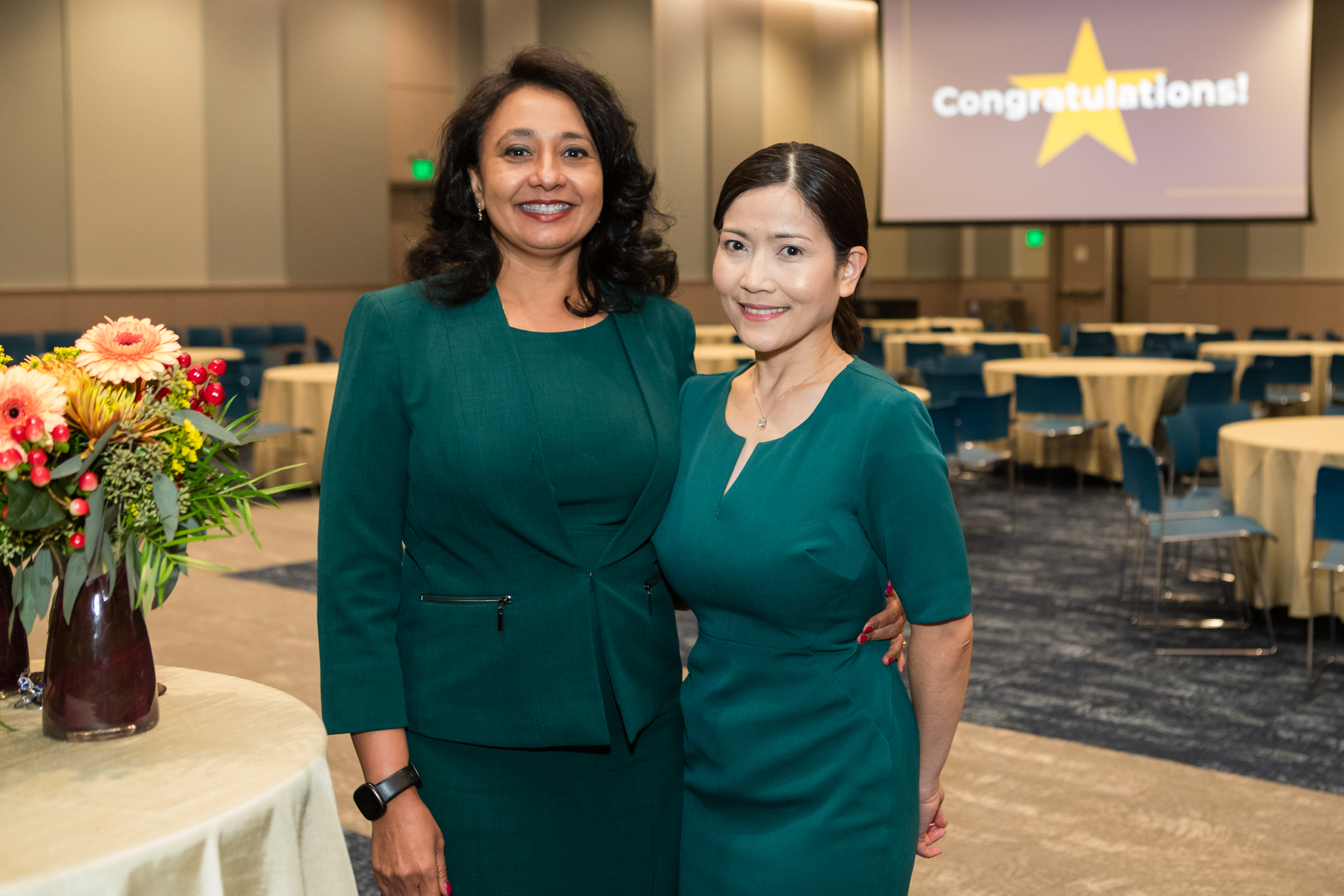 Two women stand together and smile for a photo.