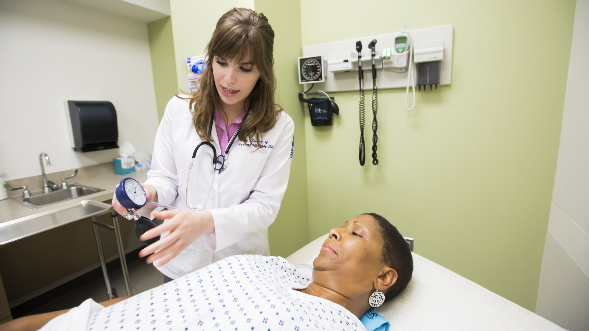 Two women look at a blood pressure monitor together in a clinical setting. 