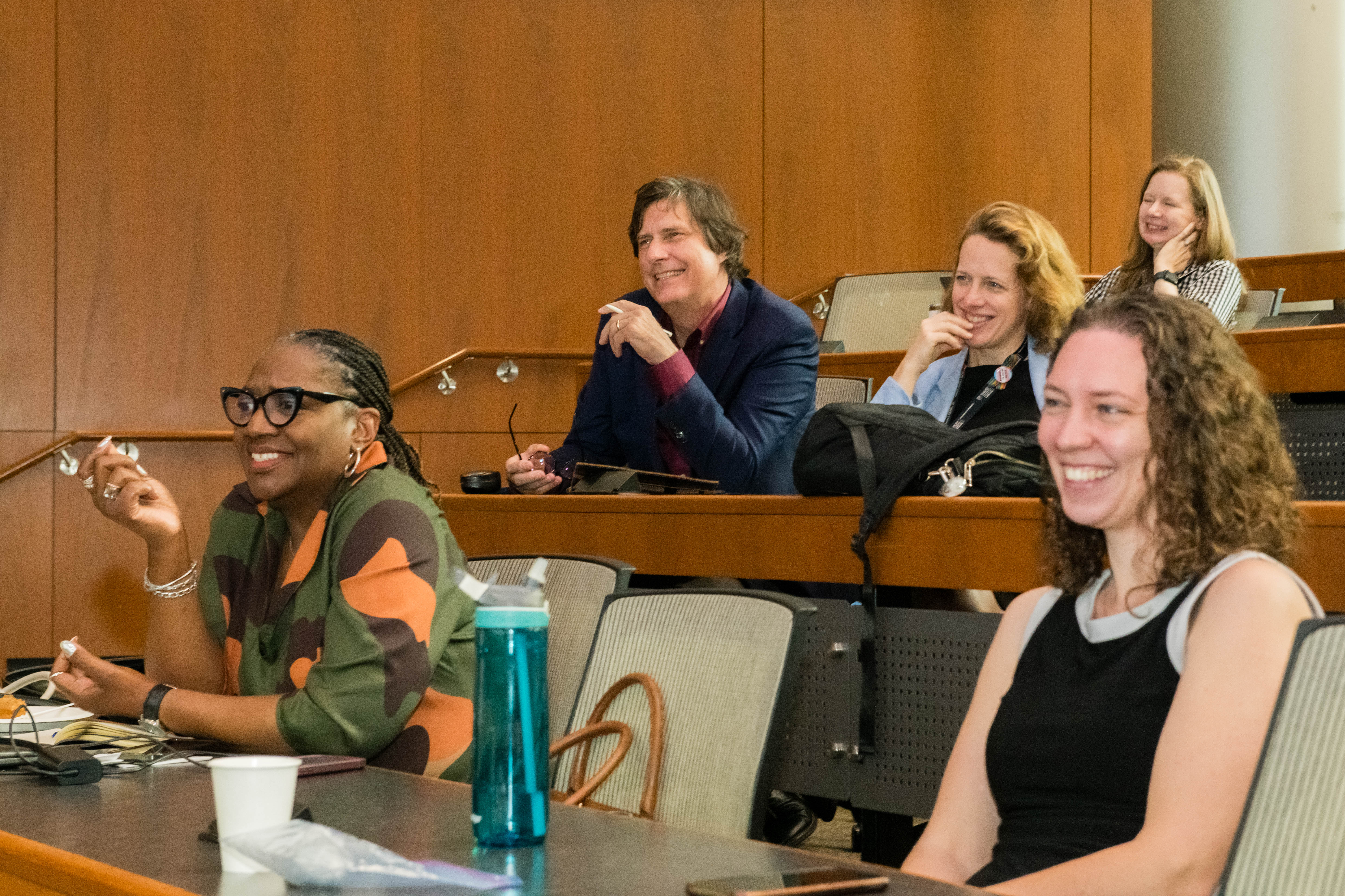 Group of people sit in a lecture hall engaging with each other.