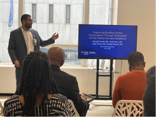 Man presents next to a screen in front of a group of people.