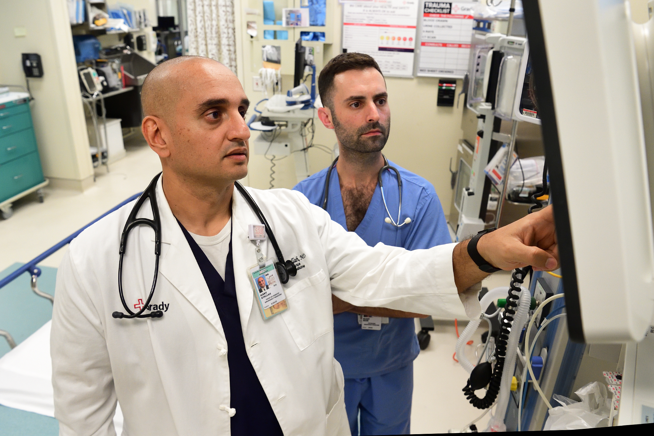 Two men review something on a screen in a hospital setting. 