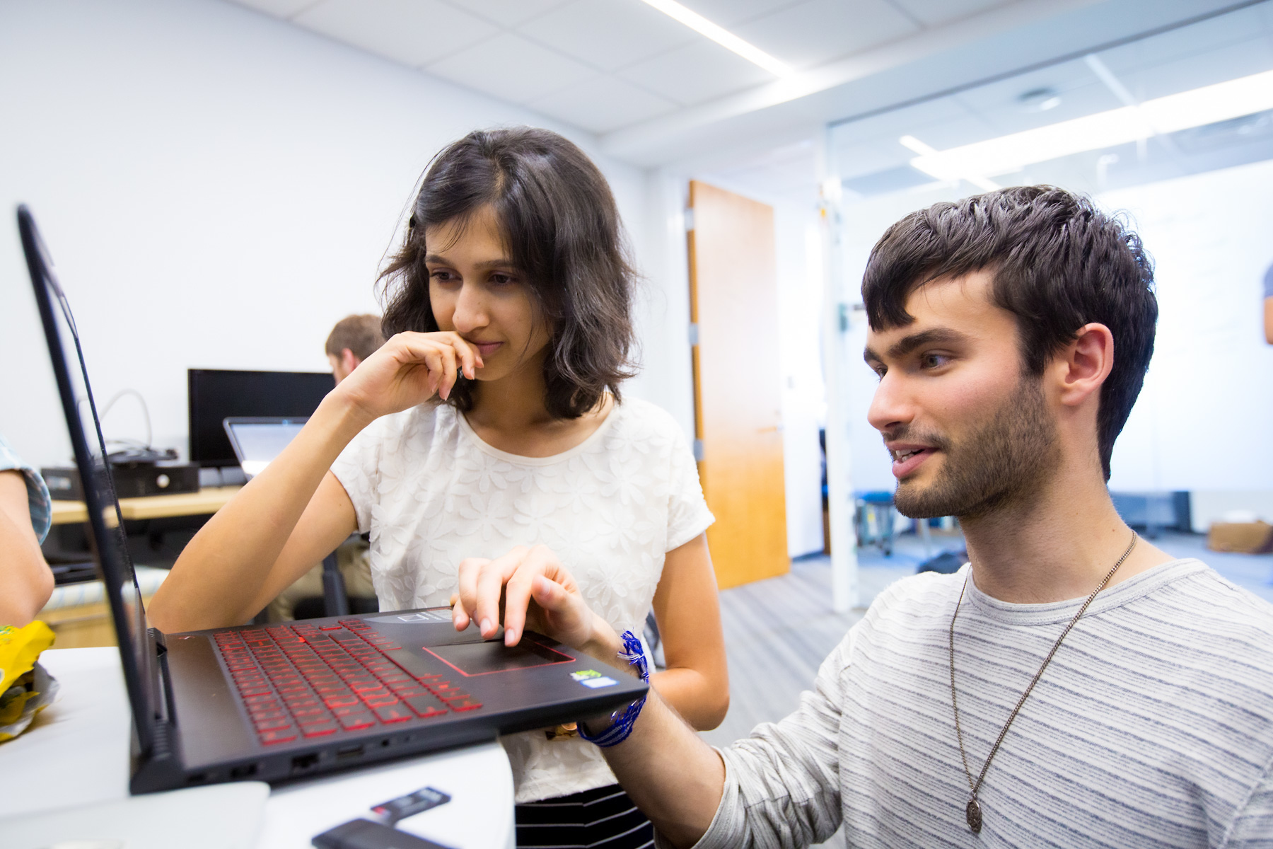 two thoughtful students sharing a laptop