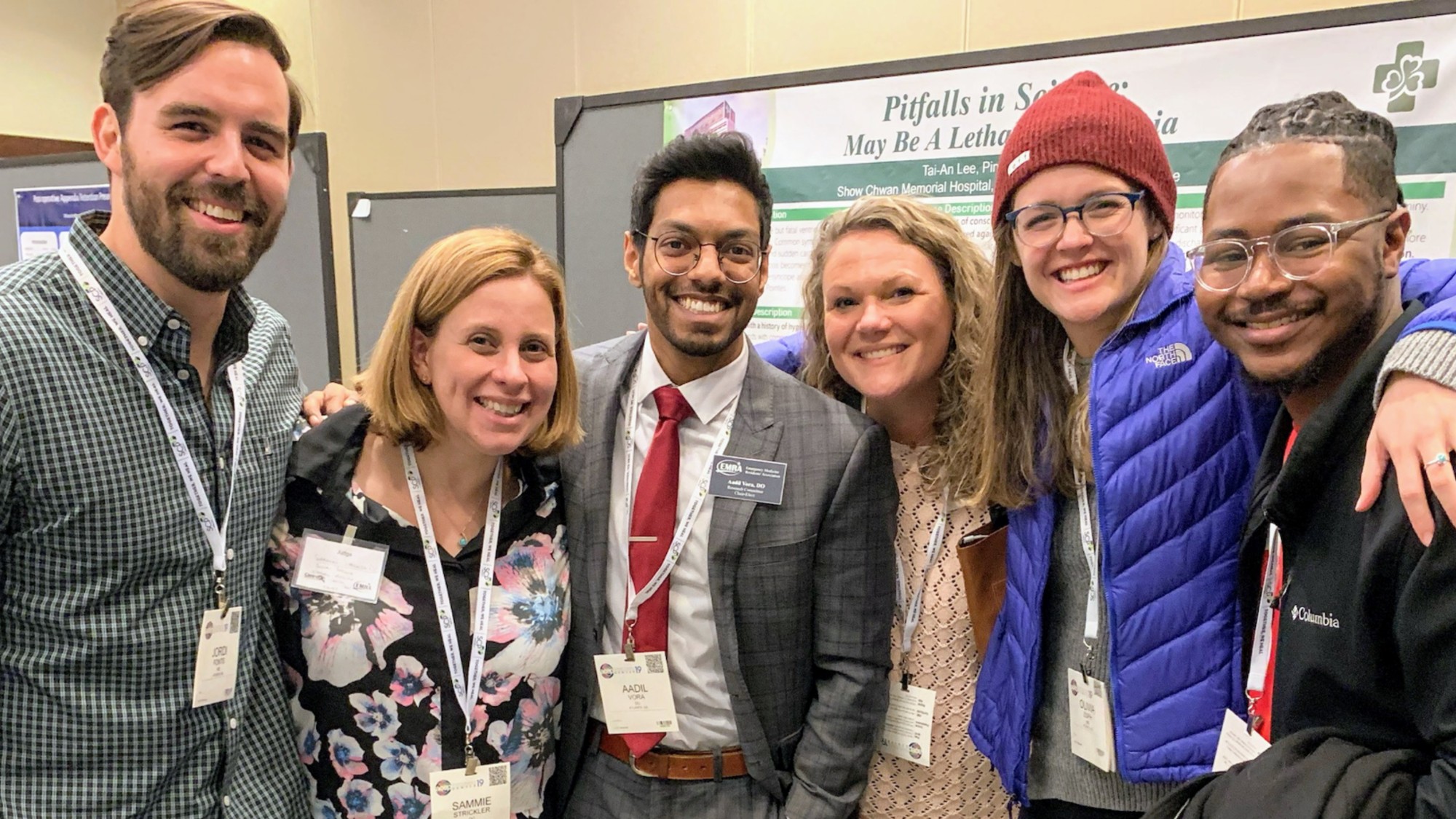 Medical residents posing in front of a research poster