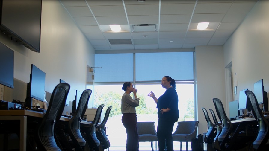 two women physicians standing in room full of computer workstations