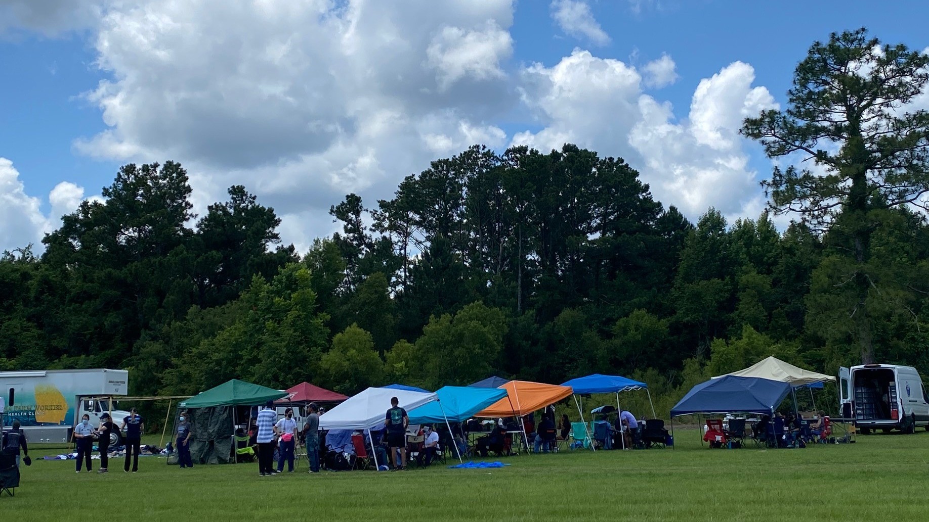 tents in a field under a blue sky with clouds