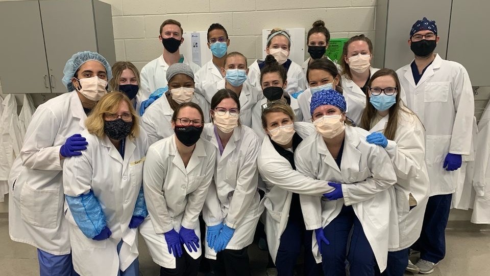 Group of masked PA students in white coats 