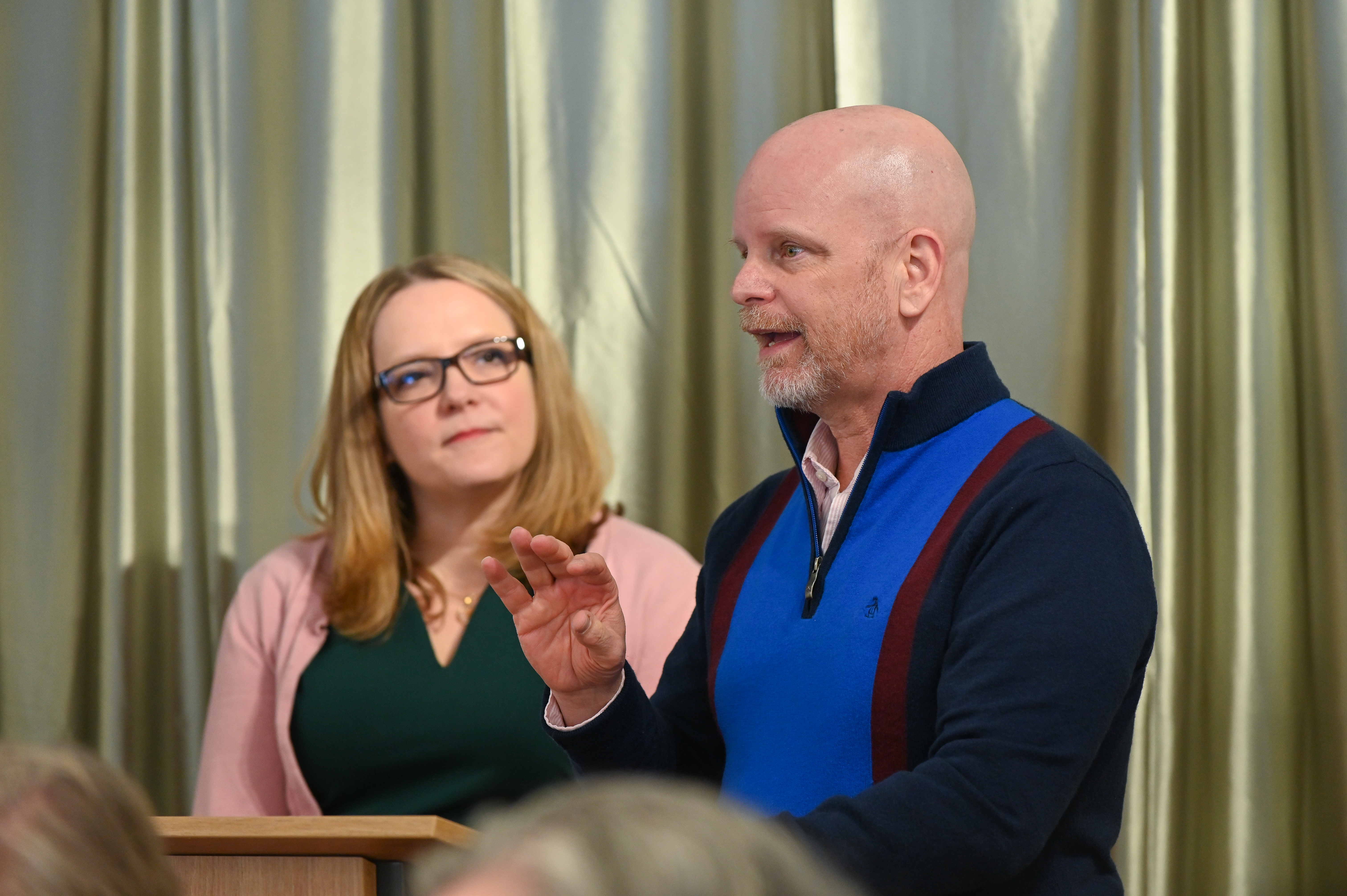 Ted Johnson speaking to others while next to Cassandra Quave at a podium.