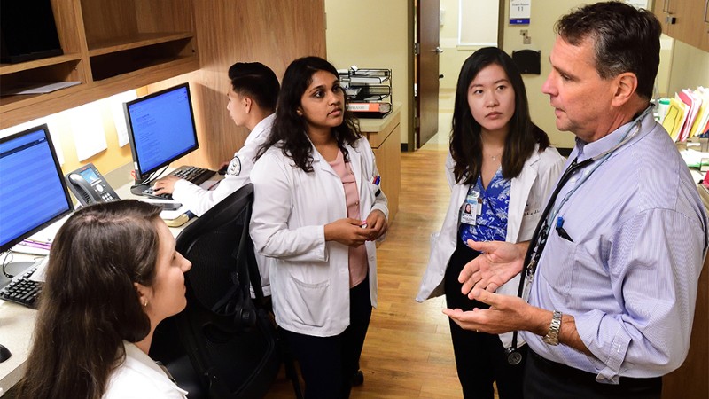 Dr. David Roberts in the clinic talking to 3 female trainees