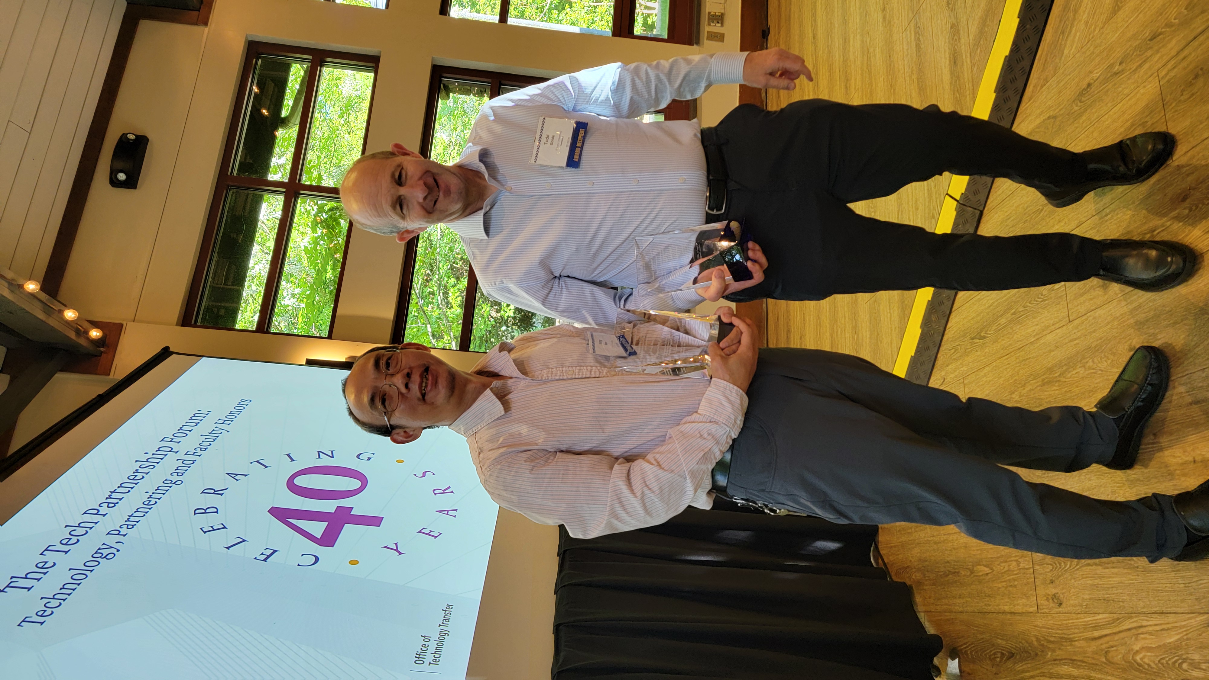 Two men standing in front of digital display screen