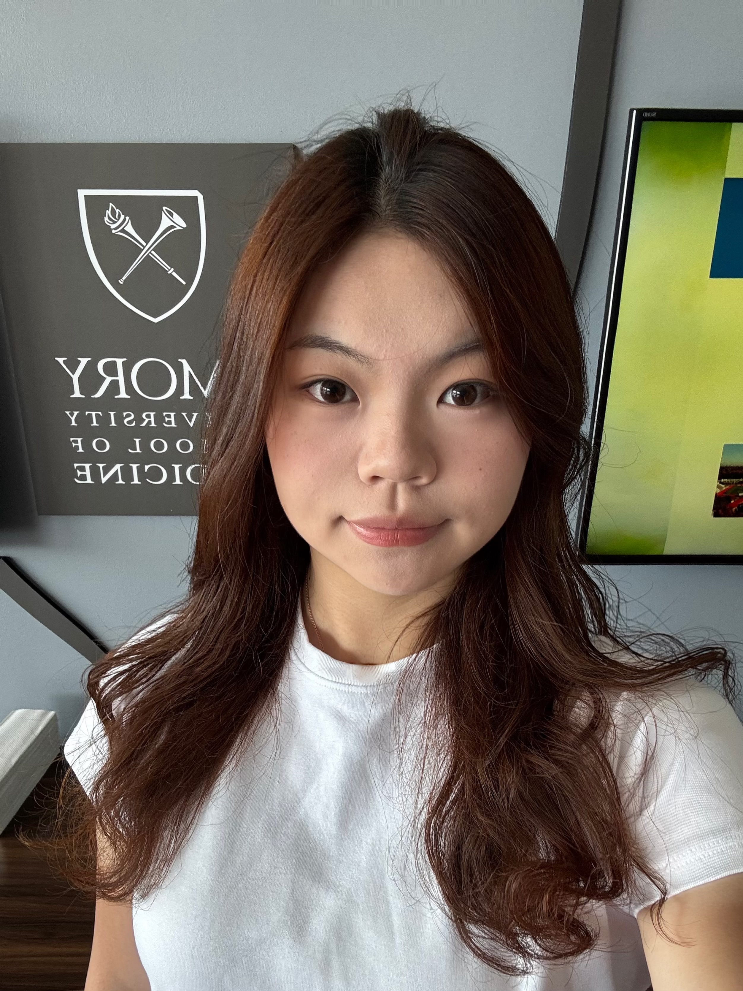 headshot of woman in white shirt standing in front of Emory sign
