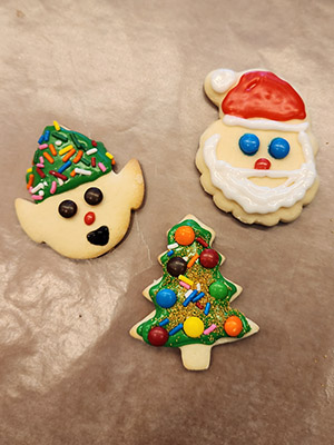 Three decorated holiday cookies on parchment paper.