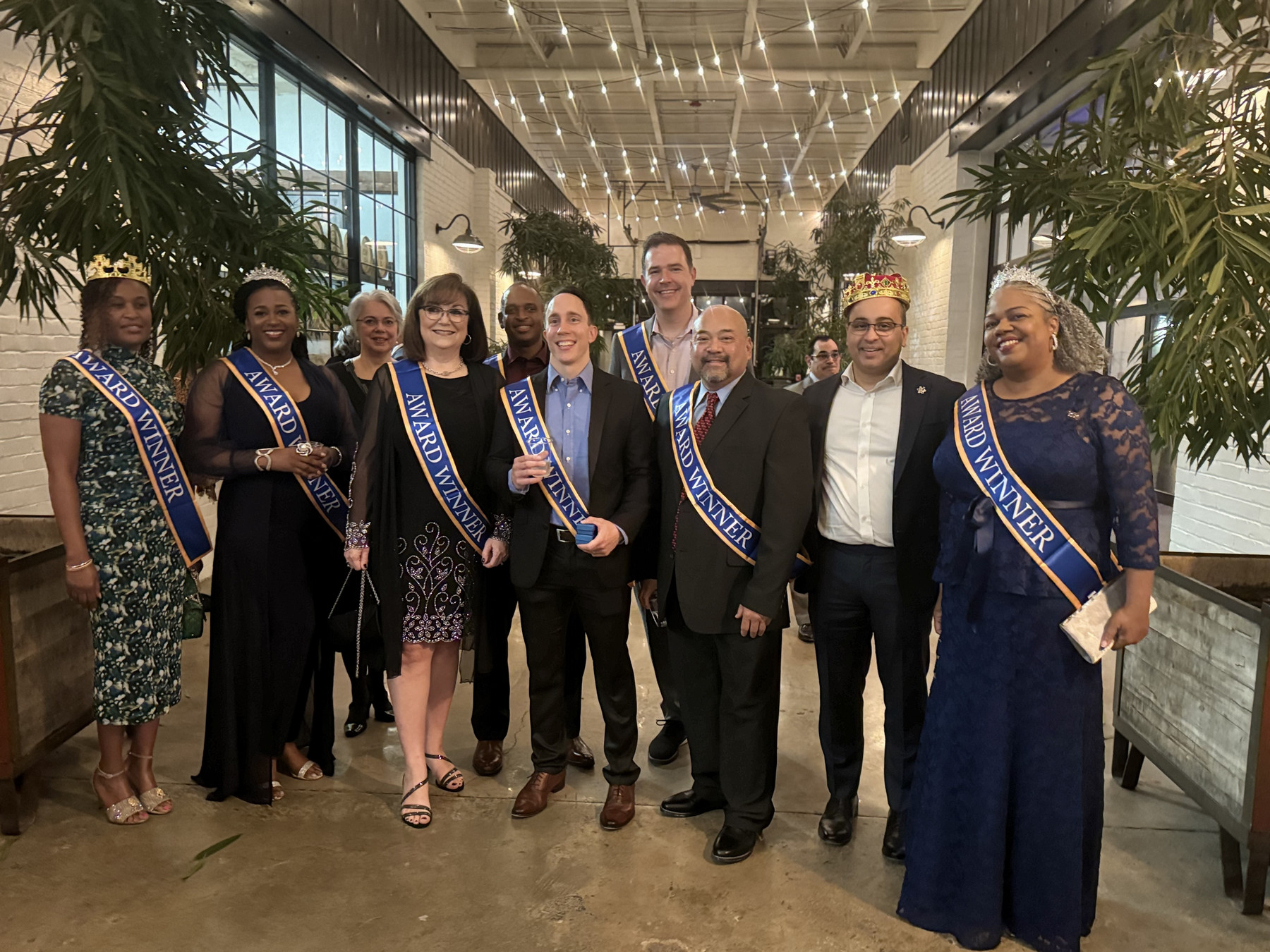 several people standing in a line wearing sashes that say 'winner'