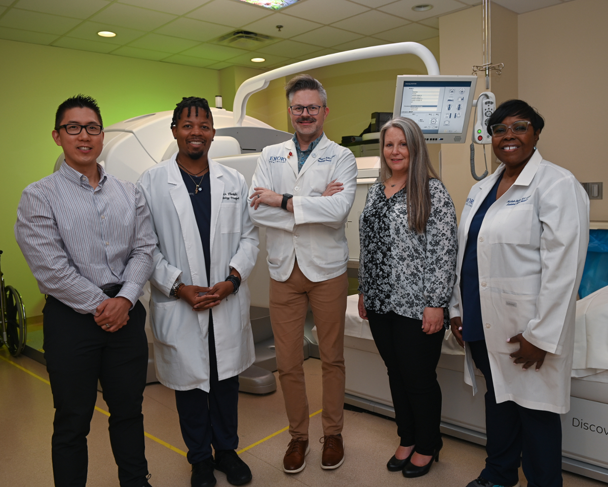 men and women wearing white lab coats standing in front of an imaging machine