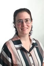 smiling person wearing specacles and a shirt with white pink brown and black stripes