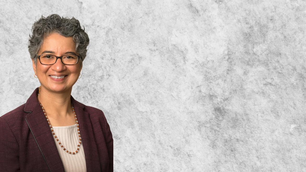 smiling person from chest up against a marbled grey background