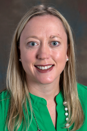 smiling woman with blond hair  and wearing a green top