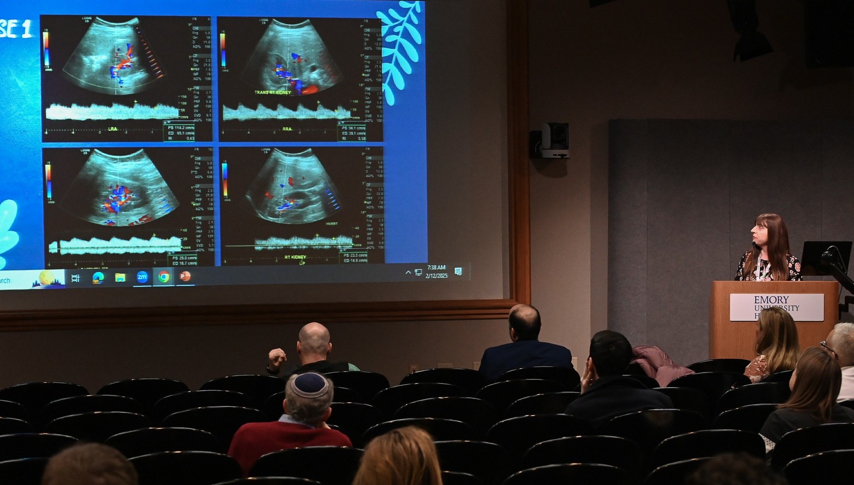 person standing at lecture talking with ultrasound images on the screen beside them