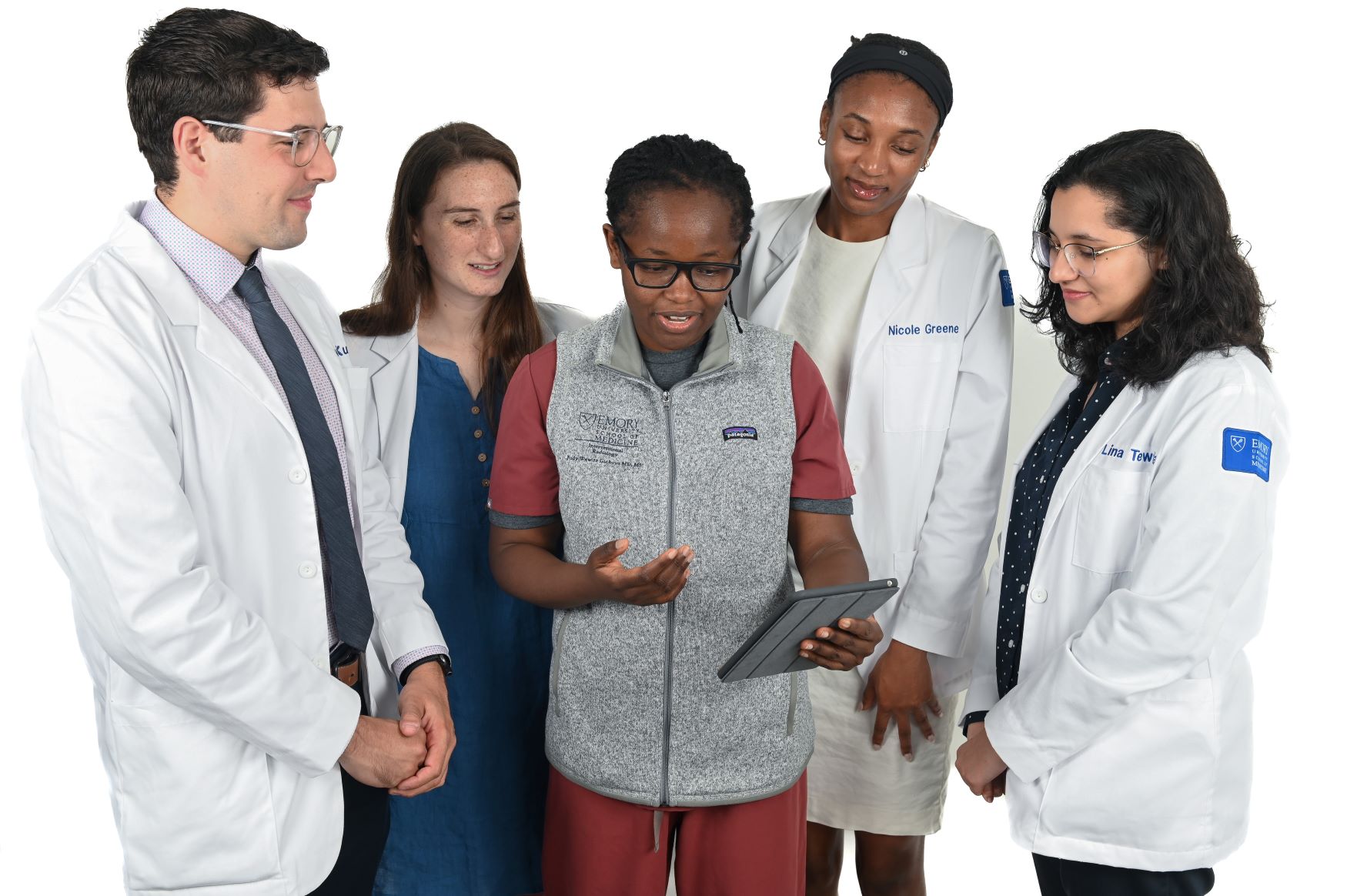 people wearing doctor coats looking over the shoulder of a doctor holding a computer tablet