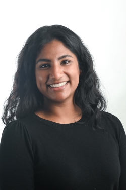 smiling woman with shoulder length black wavy hair wearing a black top