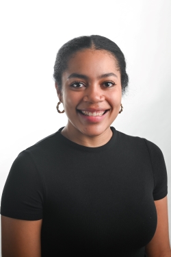 smiling woman with black hair pulled away from the face wearing gold hoop earrings and a black top