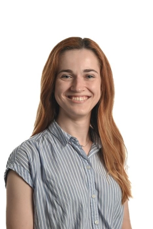 smiling person with long red hair wearing a grey and white striped short sleeved shirt