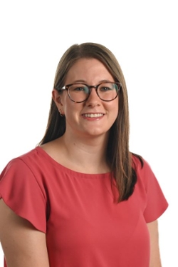 smiling person with long straight brown hair and spectacles wearing a red top