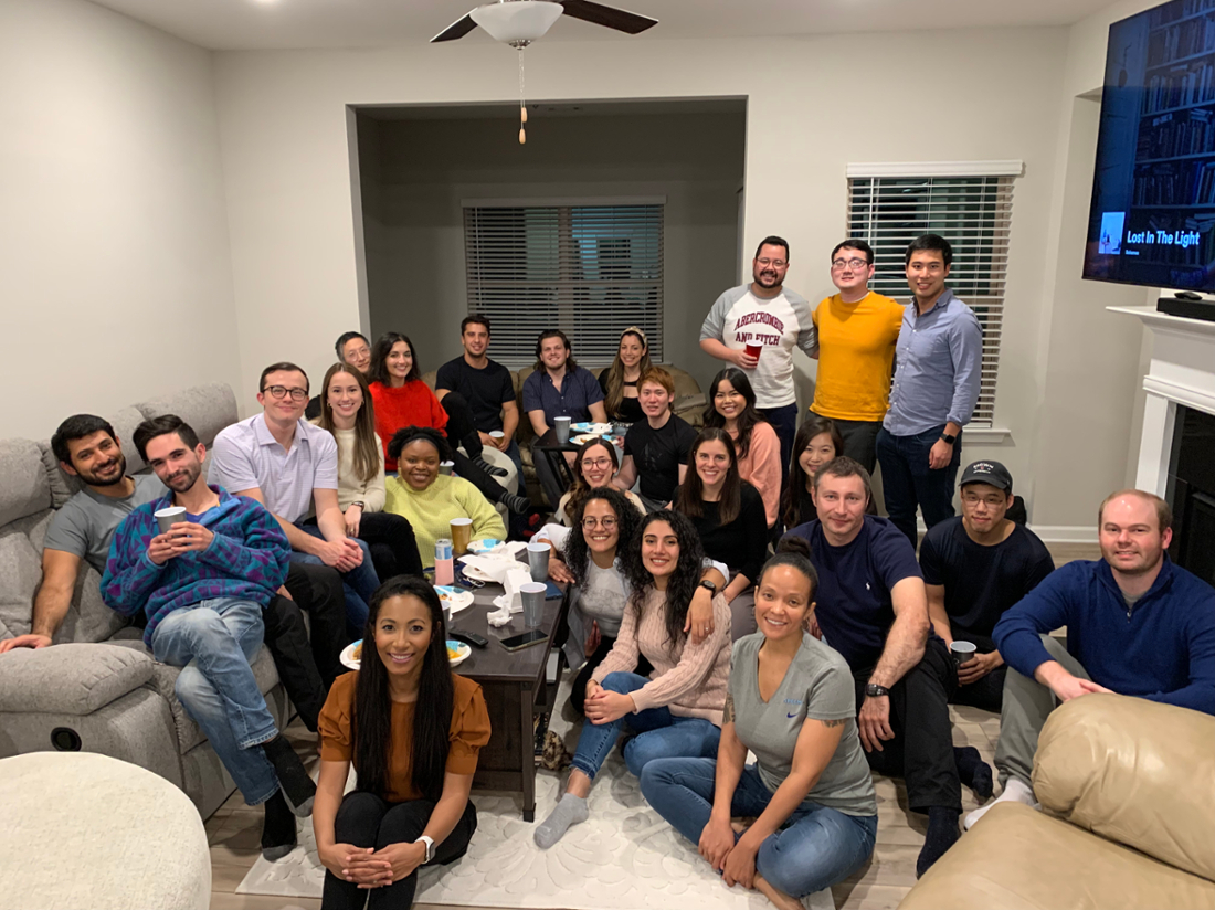 a large group of people sitting on the floor and furniture and smiling for the camera